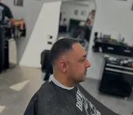 A clean low fade in profile, with the shop behind
